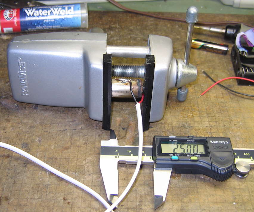 Micrometer shows exactly 25 mm as the ersatz battery is clamped in the vise